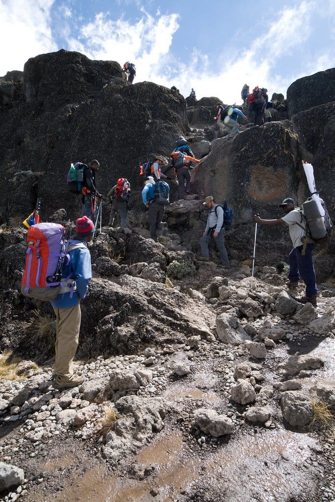 Excursionistas y porteadores trepan por las empinadas laderas rocosas de la pared de Barranco en el monte Kilimanjaro.