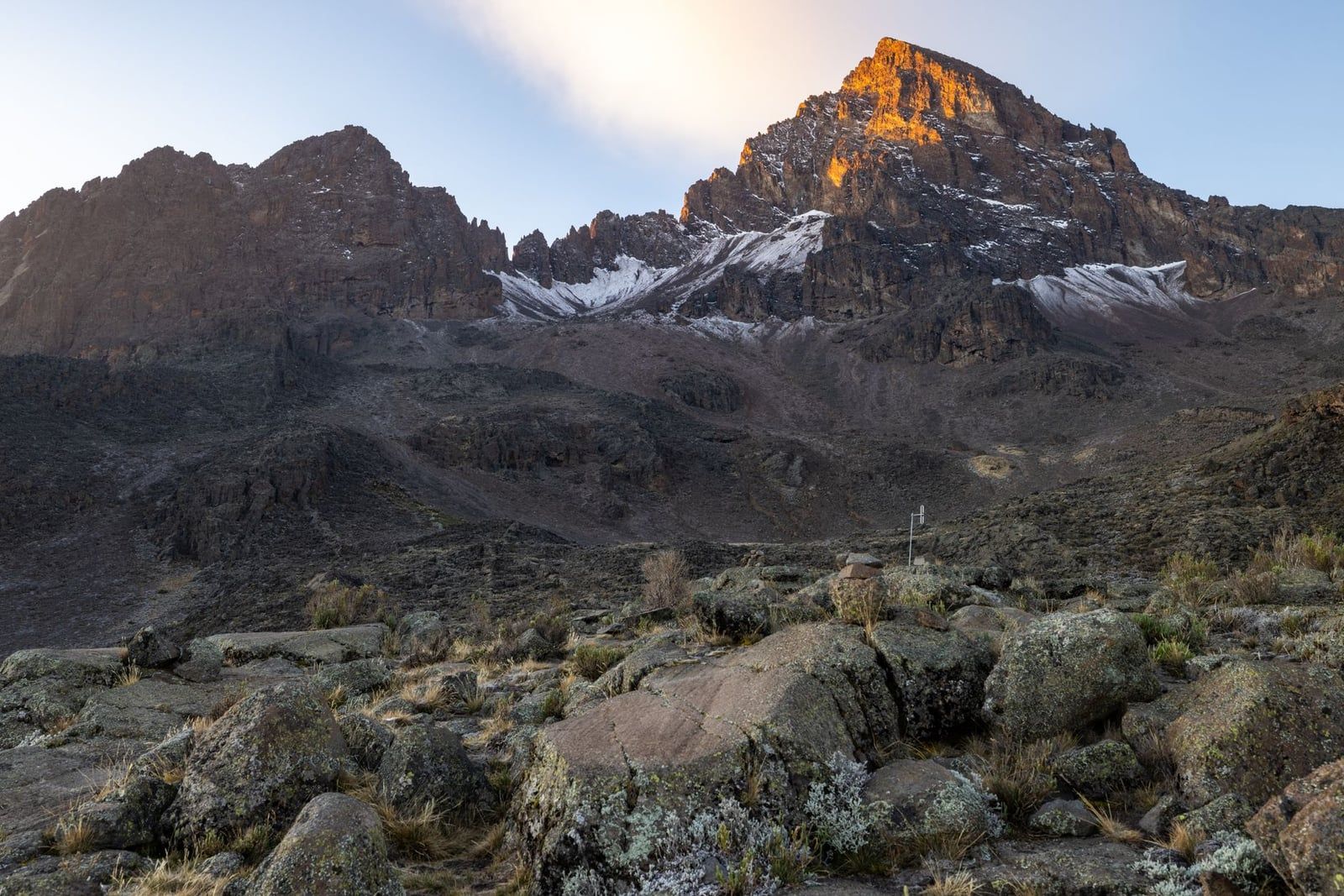 Picos rocosos y dentados del pico Mawenzi iluminados por la dorada luz solar de la mañana en el monte Kilimanjaro.